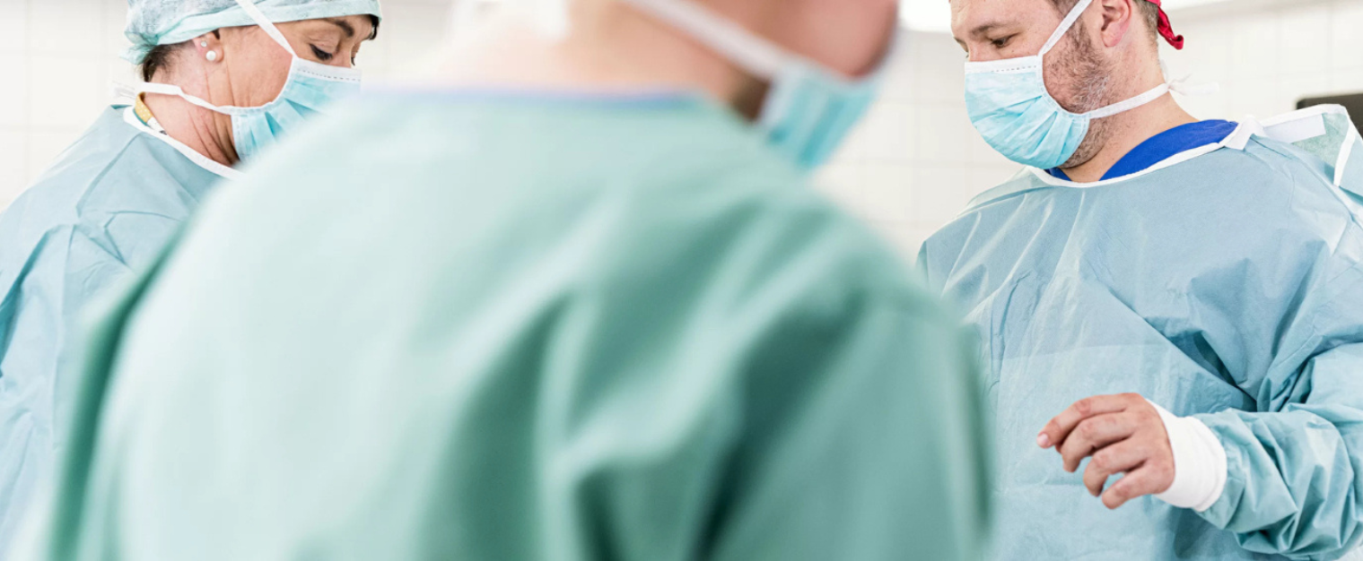 Chirurg mit Mundschutz schaut auf einen Patienten
